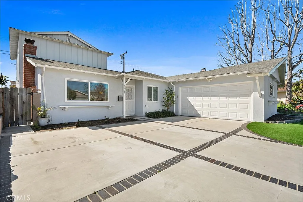 A white house California real estate with a garage and a brick driveway