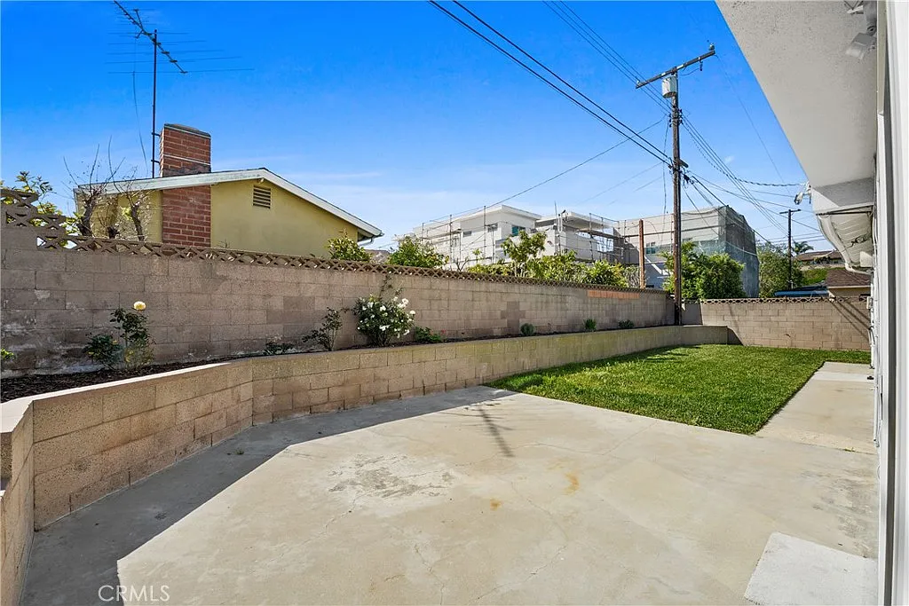 house with a green lawn, brick wall, and flowers.