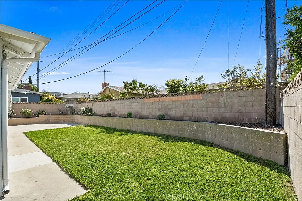 house with a green lawn, a brick wall, and a concrete path.