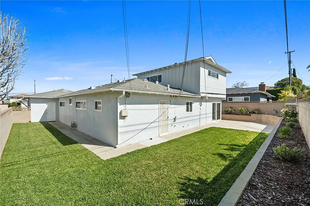 Luxury California real estate house with a green lawn and a low wall.