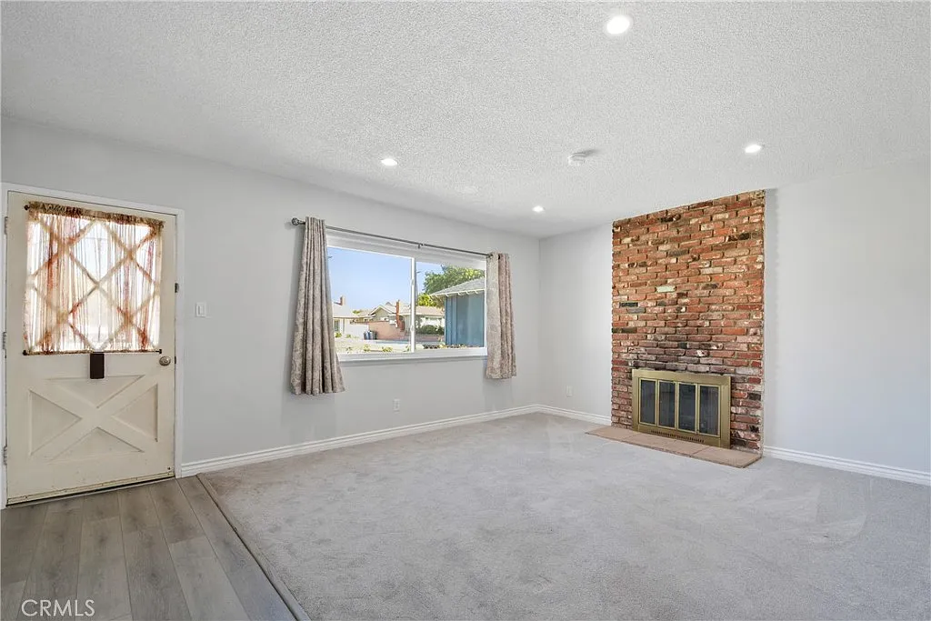 living room with a brick fireplace, a large window, and light-colored walls.