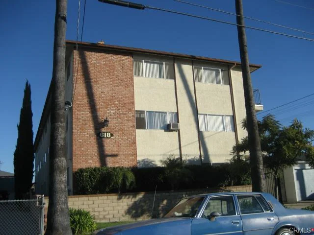 Building with brick, stucco, balconies, palm trees, and plants