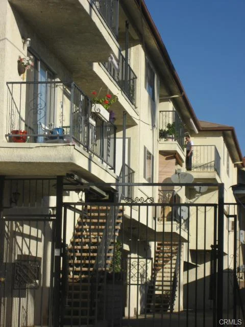 Building with balconies, stairs, gate, and flower pots