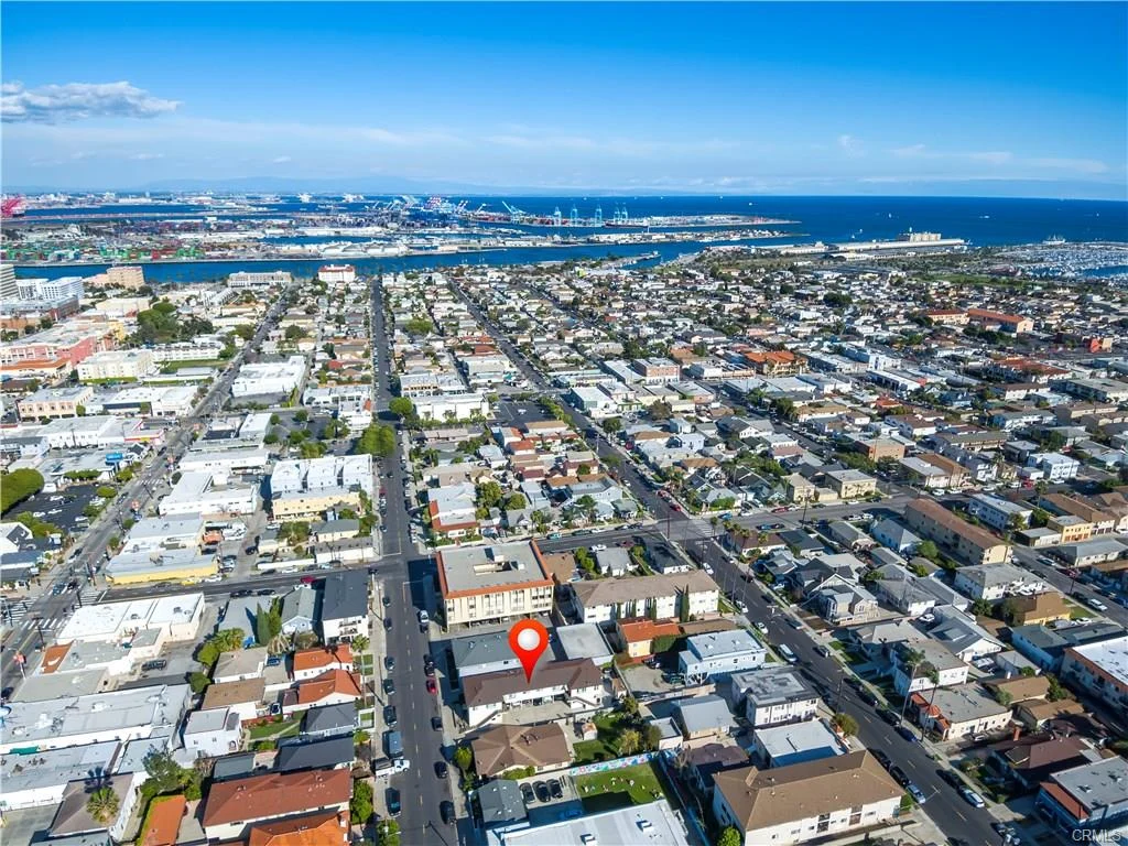 Aerial view of houses, buildings, ocean, and location marker