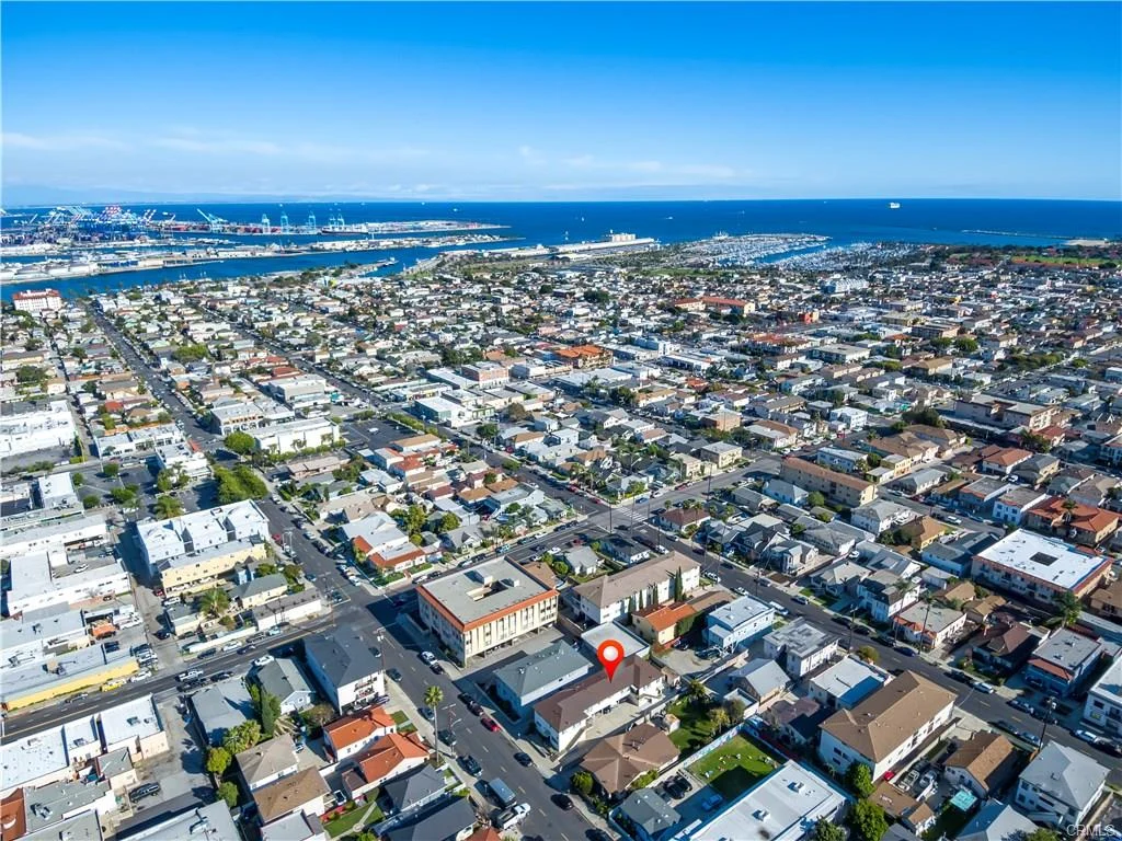 Aerial view of houses, streets, ocean, boats, and map marker