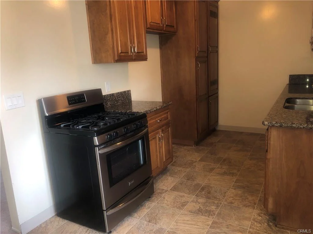 Small bathroom with wood cabinet, granite counter, sink with two faucets, and toilet