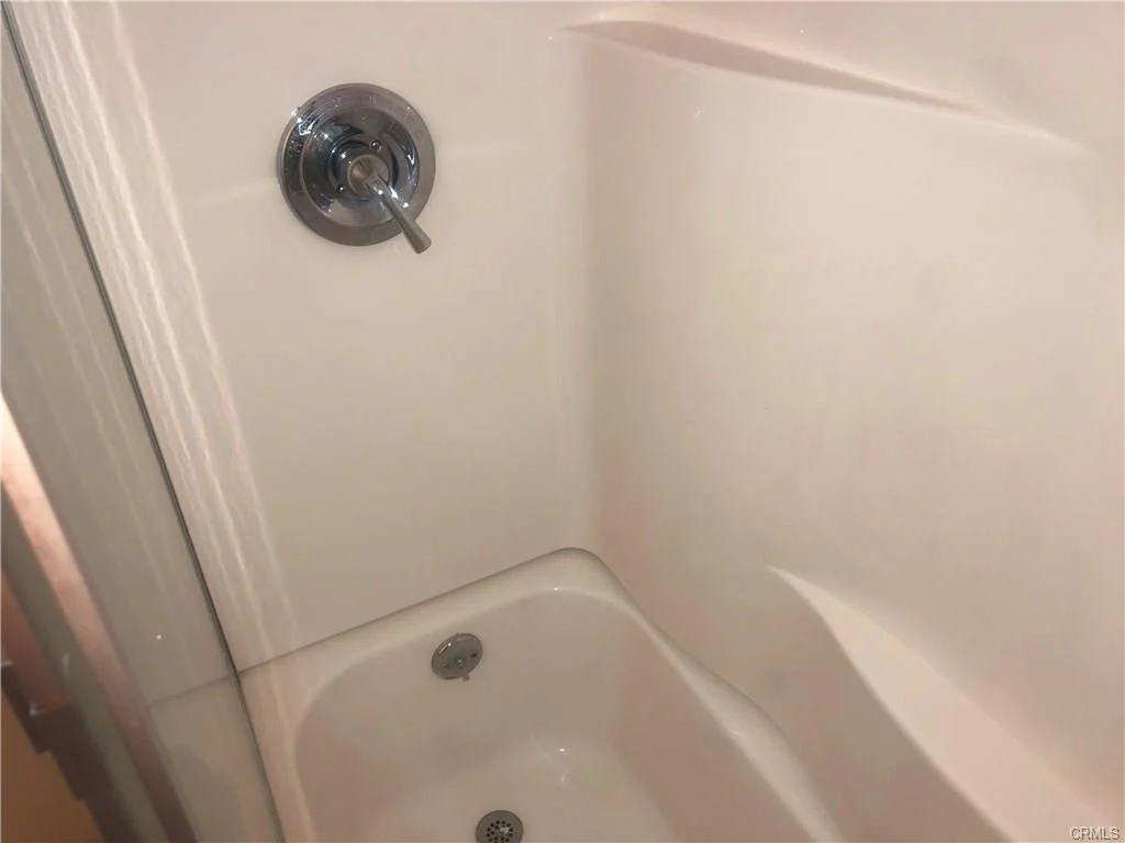 Shower with chrome faucet and knob on light wall