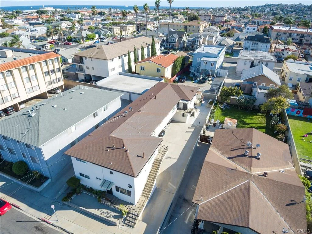Aerial view of houses, apartments, roads, trees, and ocean