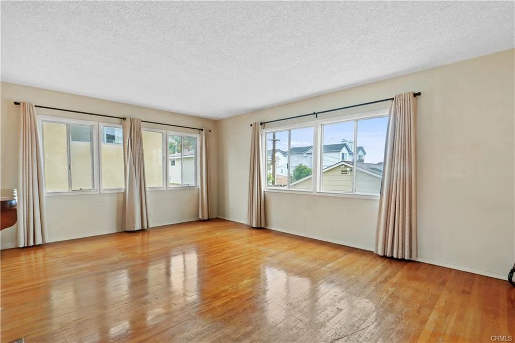 Empty room with wood floors and big windows.