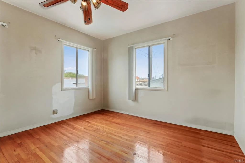 Empty room with wood floors and two windows.