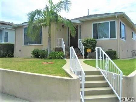 Single-story house California real estate with lawn, palm tree, walkway, large windows, and white railings
