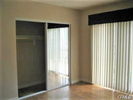 Room with mirrored closet doors, window, and light-colored walls