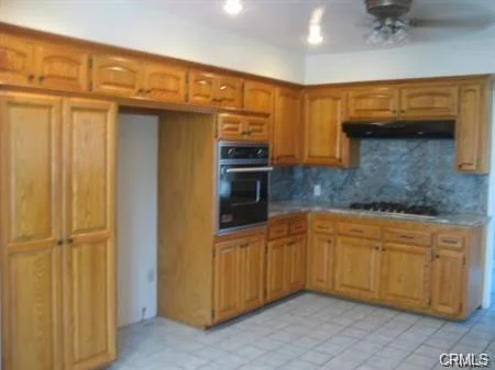 Kitchen with wooden cabinets, built-in oven, gas stove, and tile floor